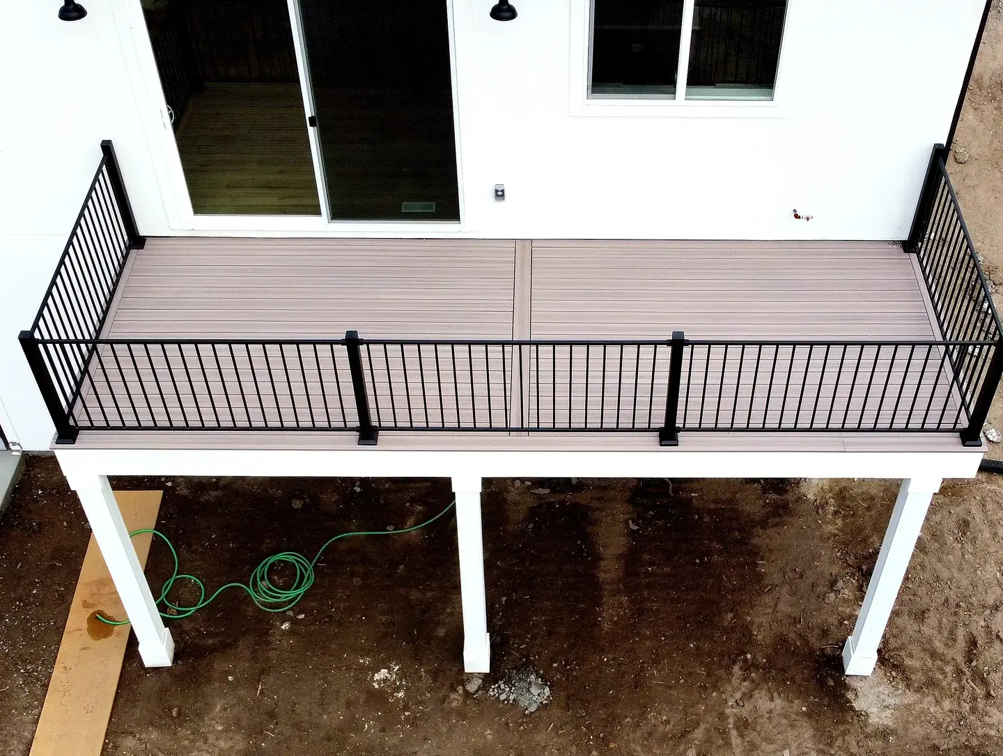 Second-story deck with black aluminum railing and white posts