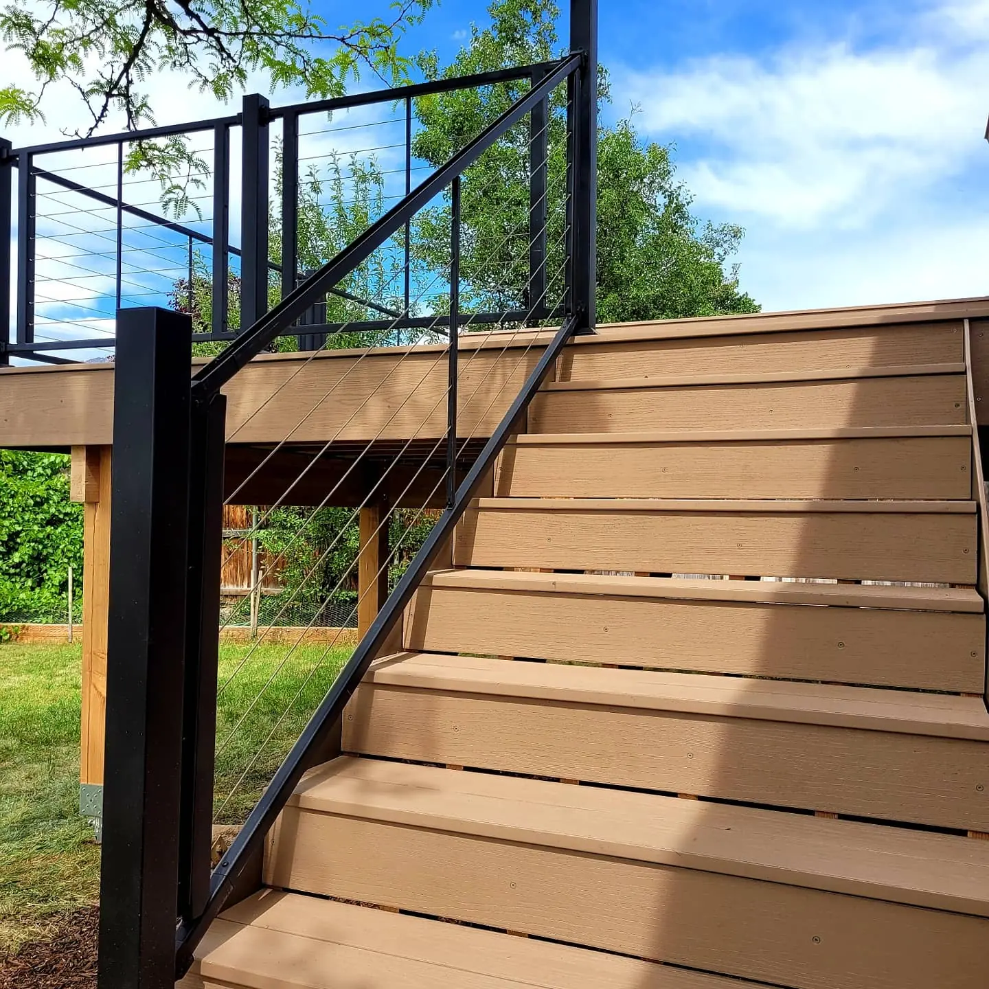 Glass panel railing along wide composite deck stairs