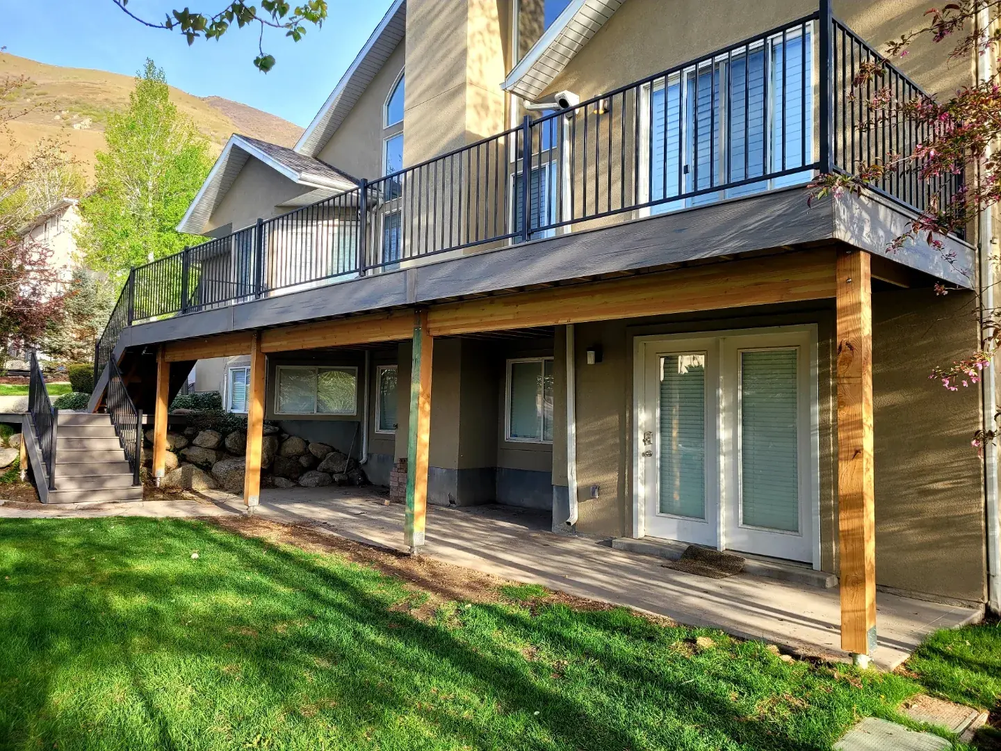 Large second-story composite deck with black railing and wood posts