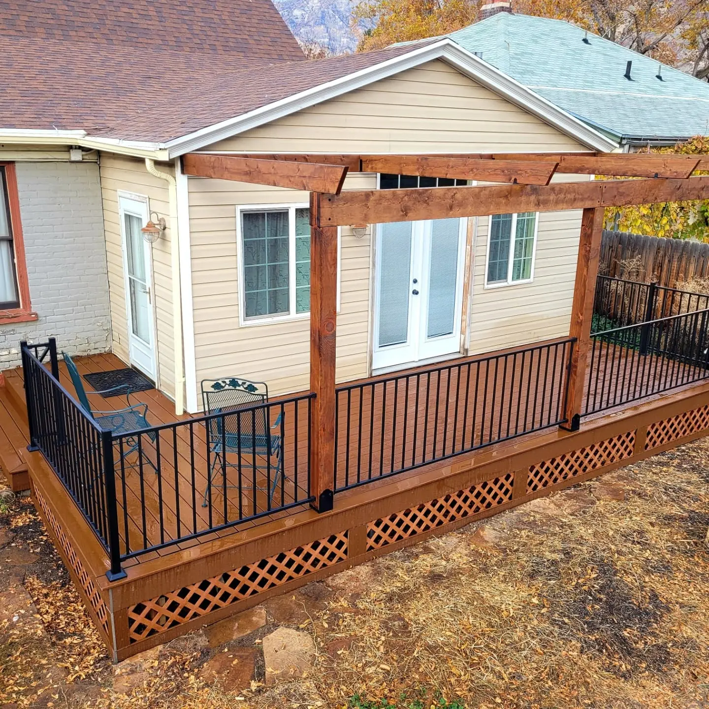 Stained pergola with black railing and lattice skirting
