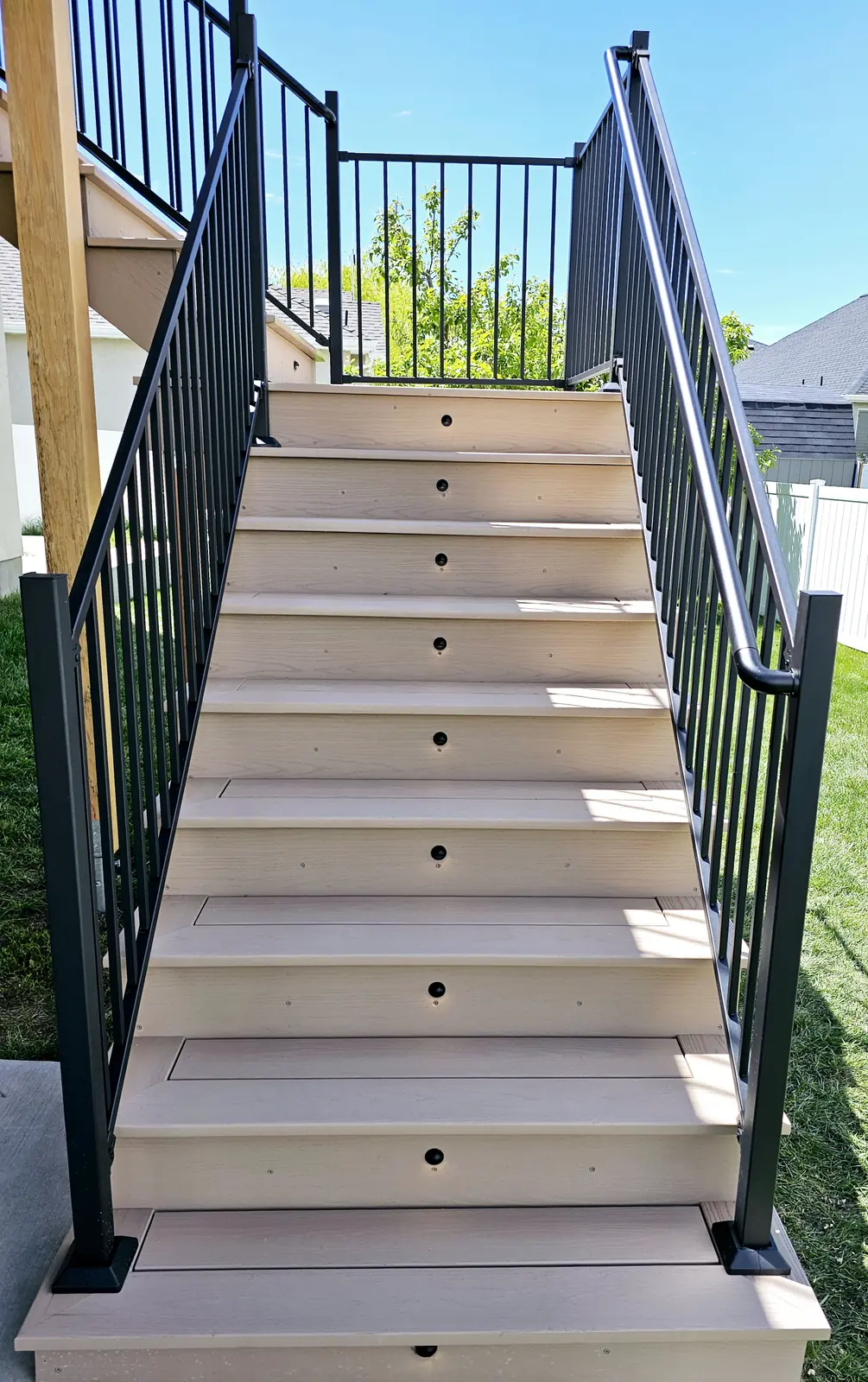 Composite deck stairs with black railing in daylight