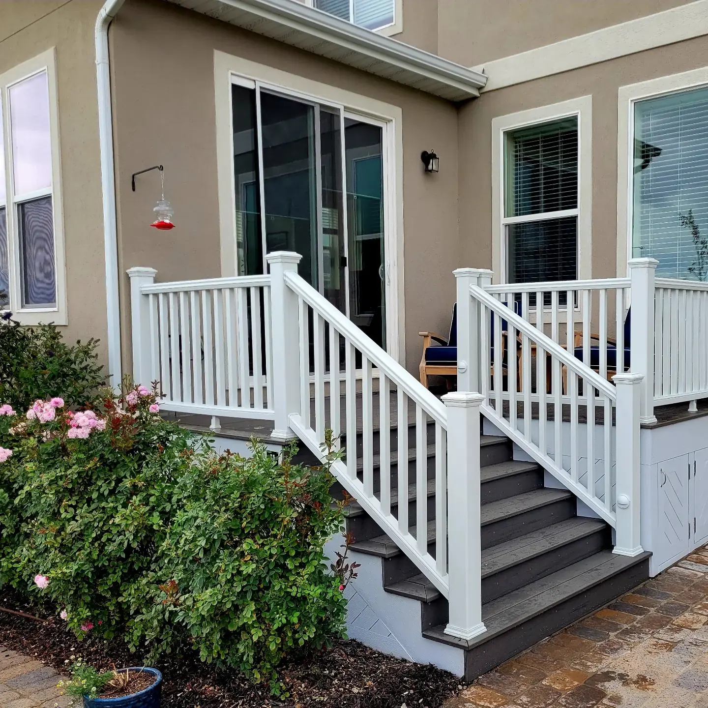 Raised back porch with white vinyl railing and dark composite stairs