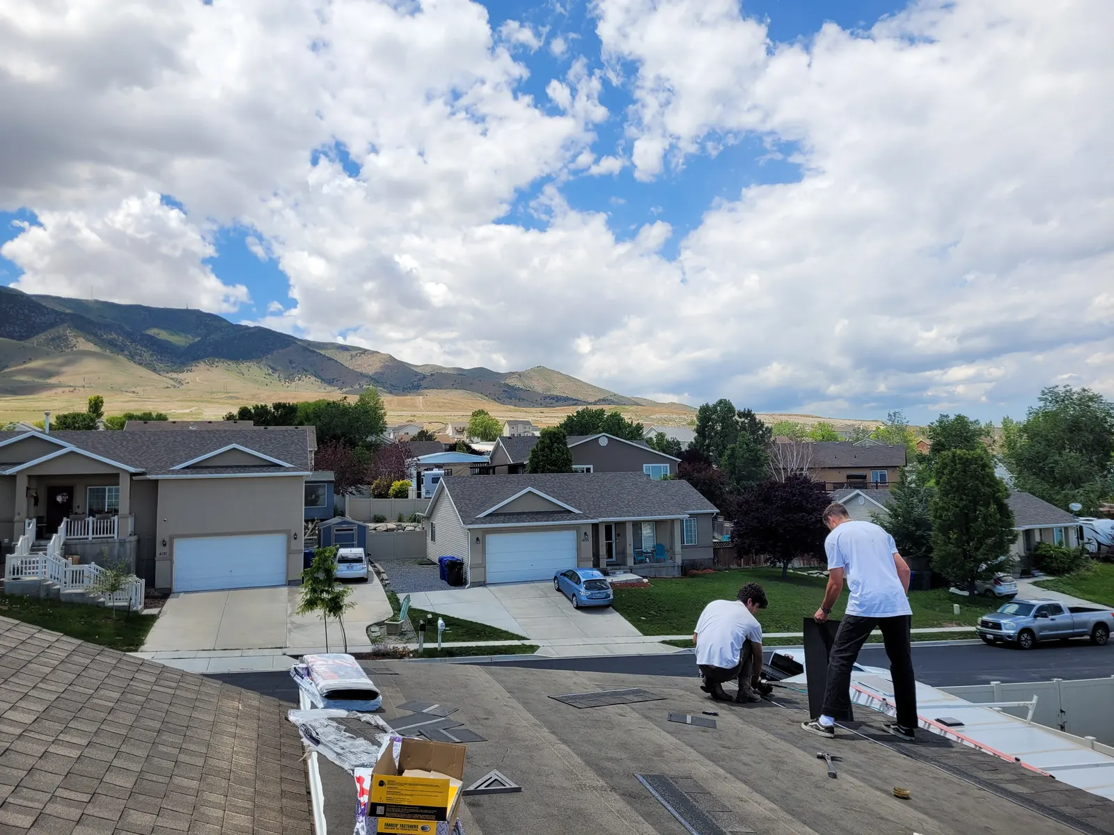 Crew installing shingles on the new deck roof with mountain views