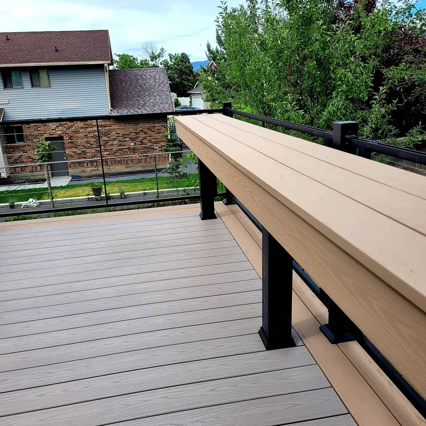 Built-in Brownstone deck bench on black posts along the railing