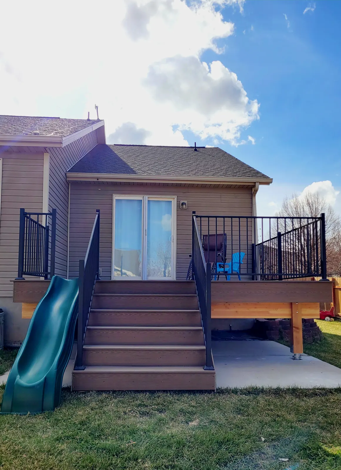 Raised composite deck with stairs and a green slide in Eagle Mountain, Utah