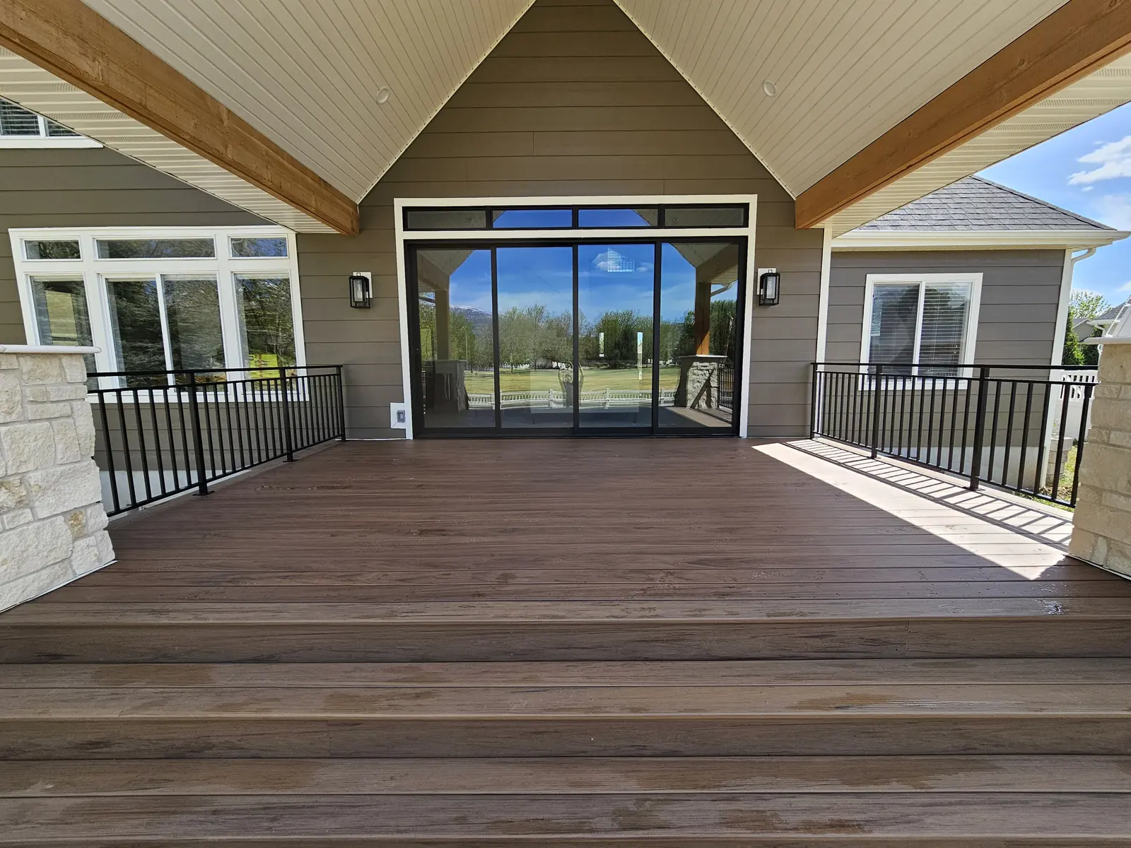 Wide TimberTech Legacy Pecan steps leading up to a covered deck with black railing