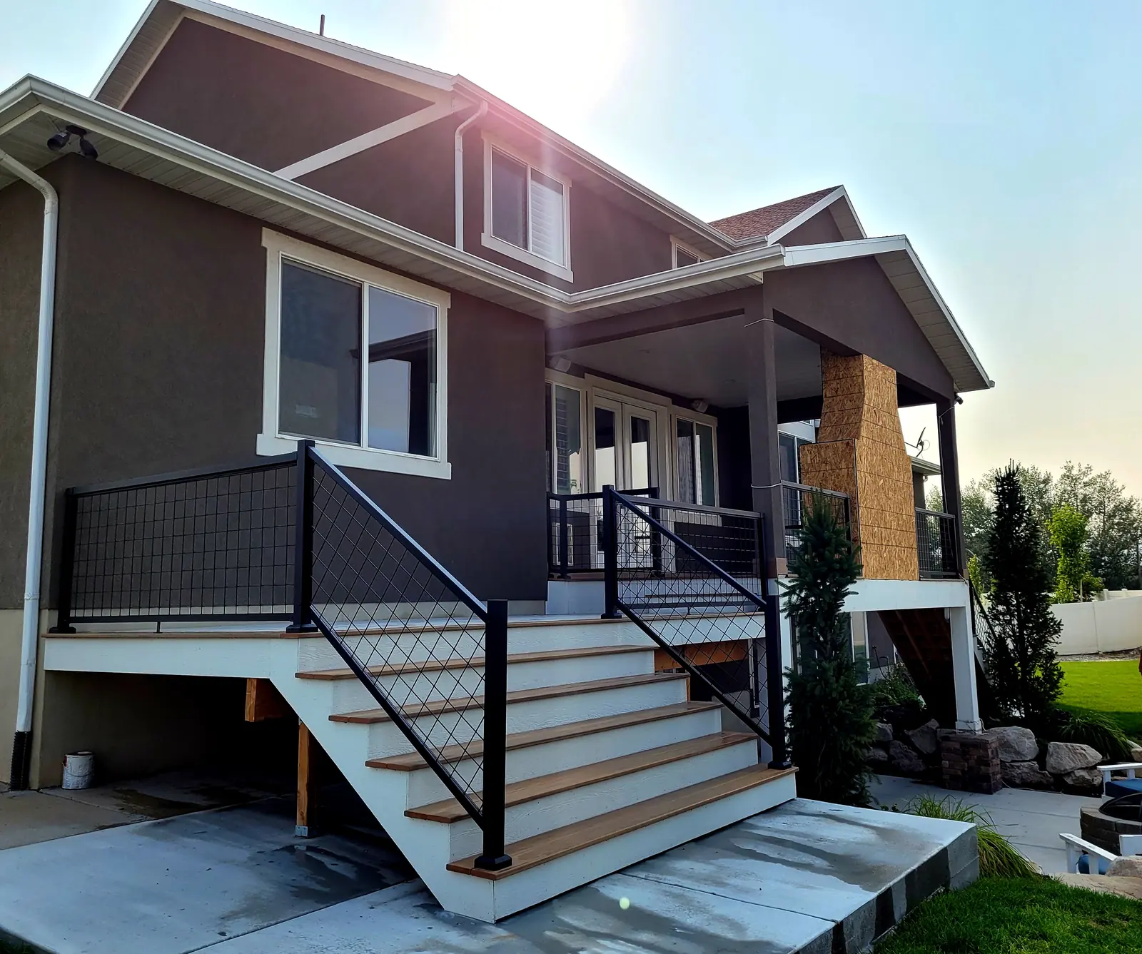 Covered composite deck with a stone fireplace and stairs in Lehi, Utah