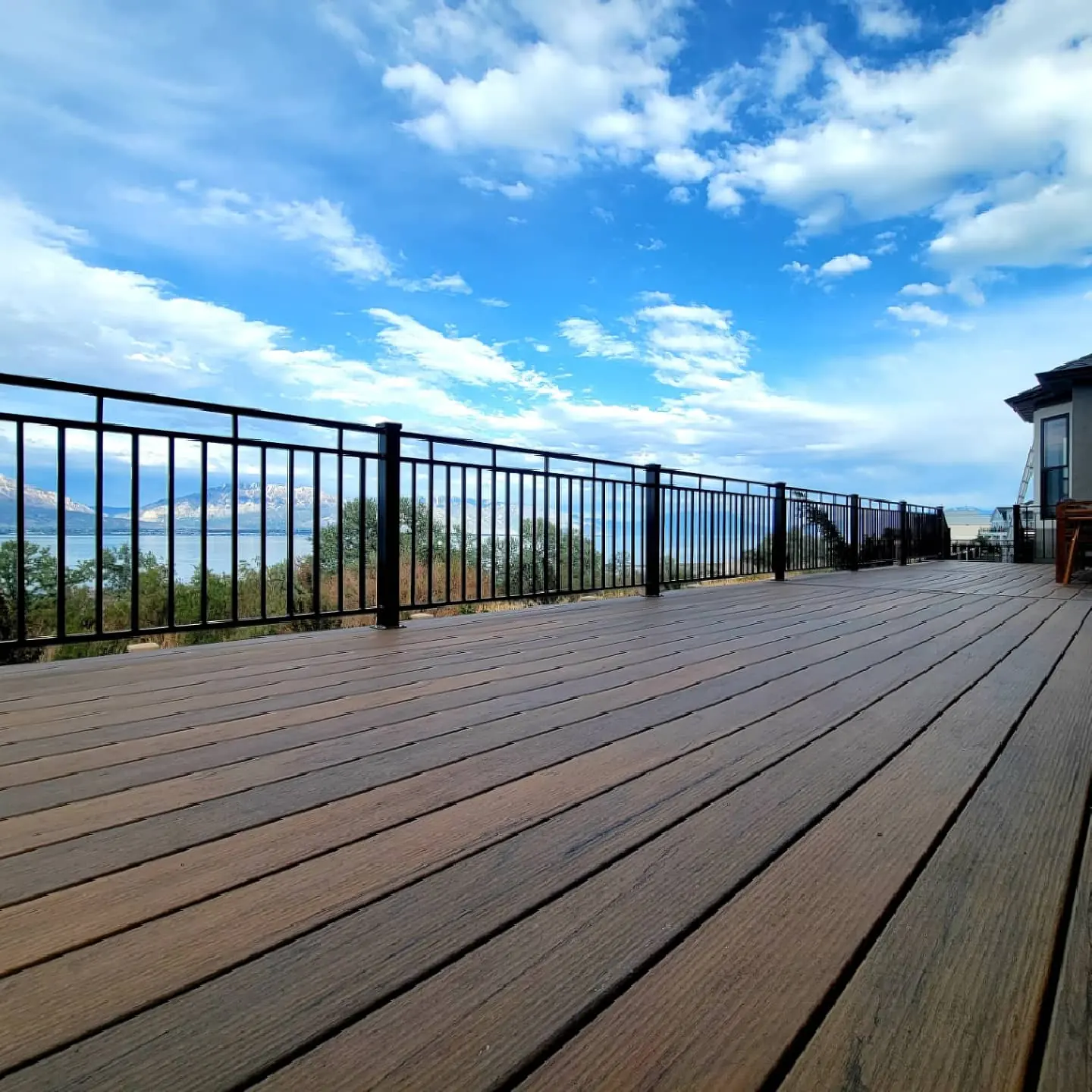 Low view across Tiger Wood deck boards to black metal railing and Utah Lake