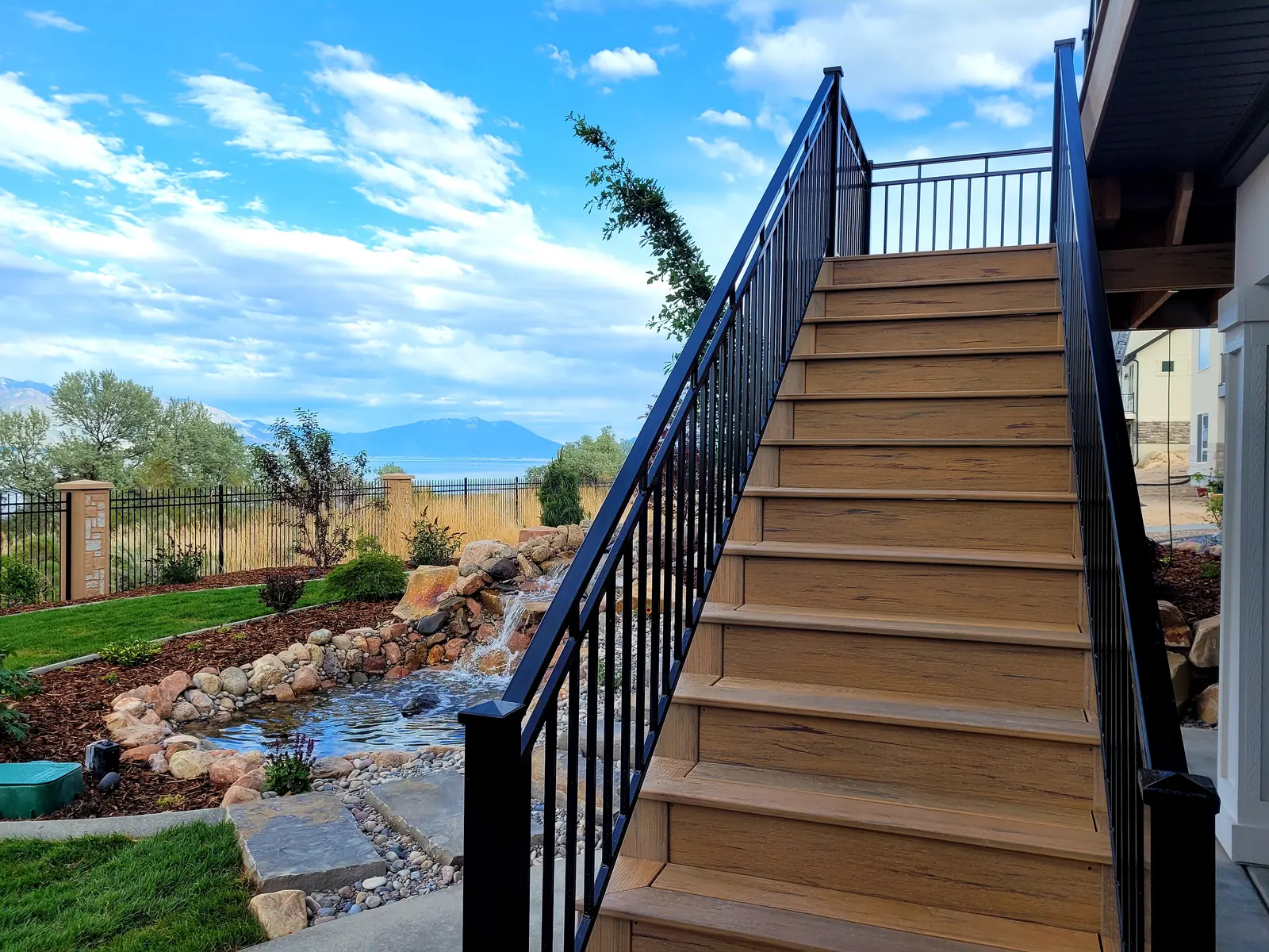 Long composite stair run with black metal railing down to the yard
