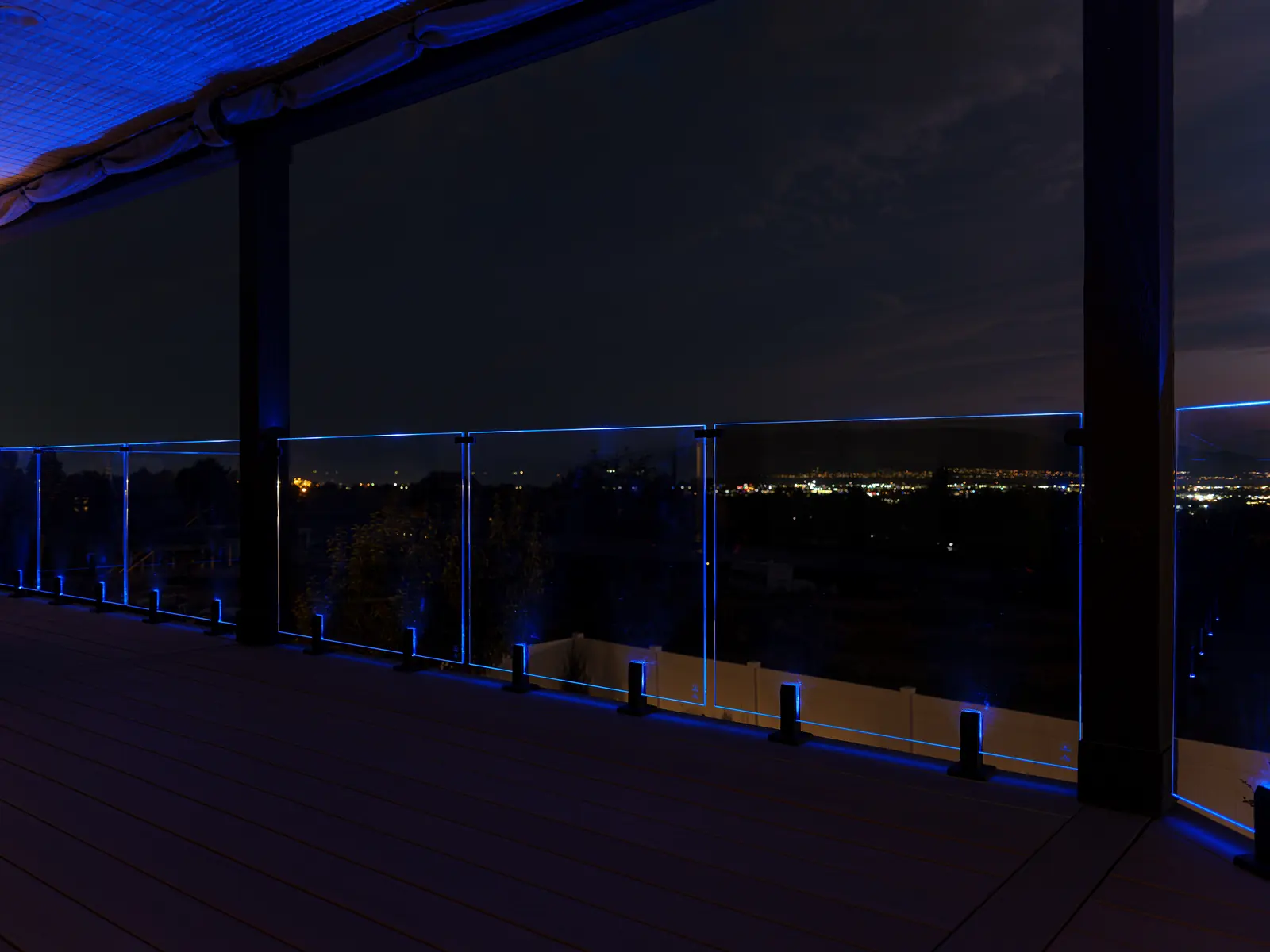Covered deck with illuminated glass railing at night