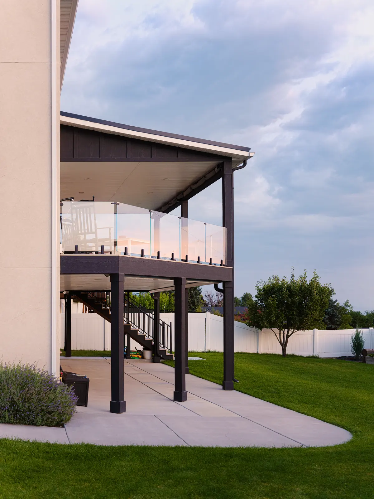 Second-story covered deck with glass railing and dark posts