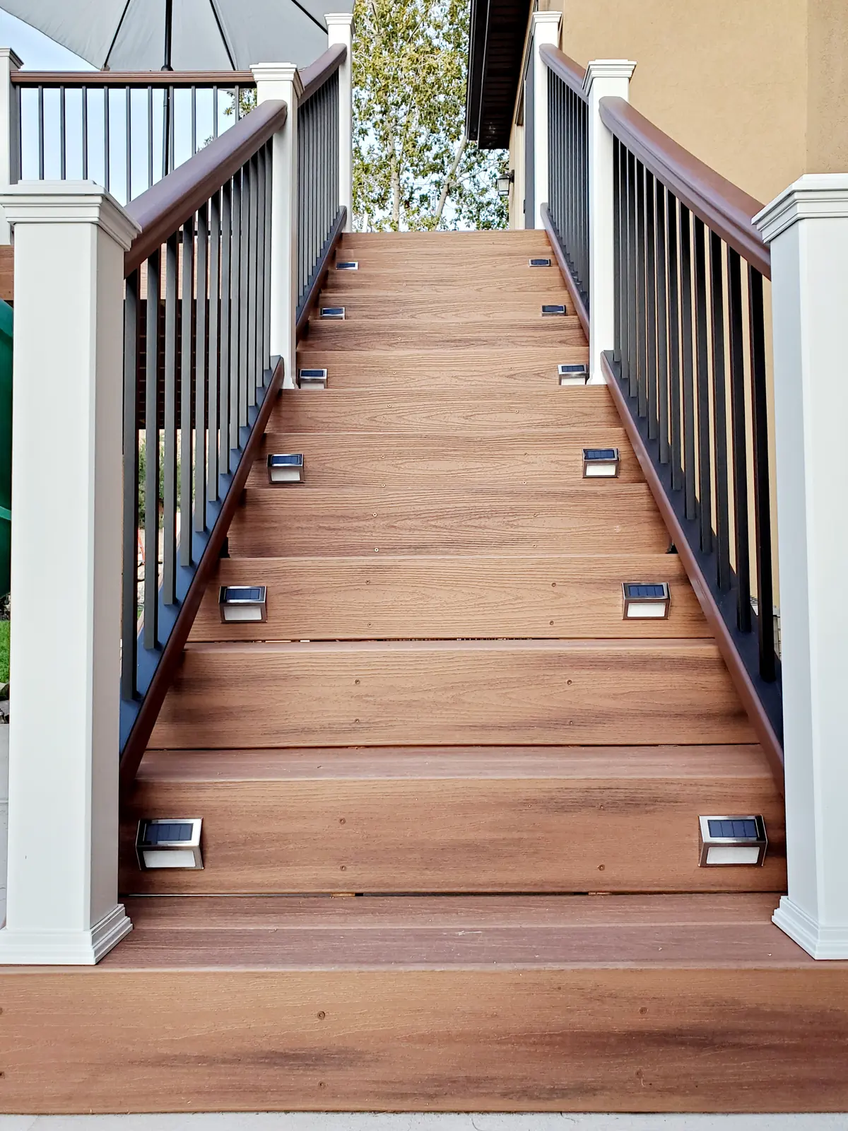 Composite deck stairs with white posts, black balusters and step lights