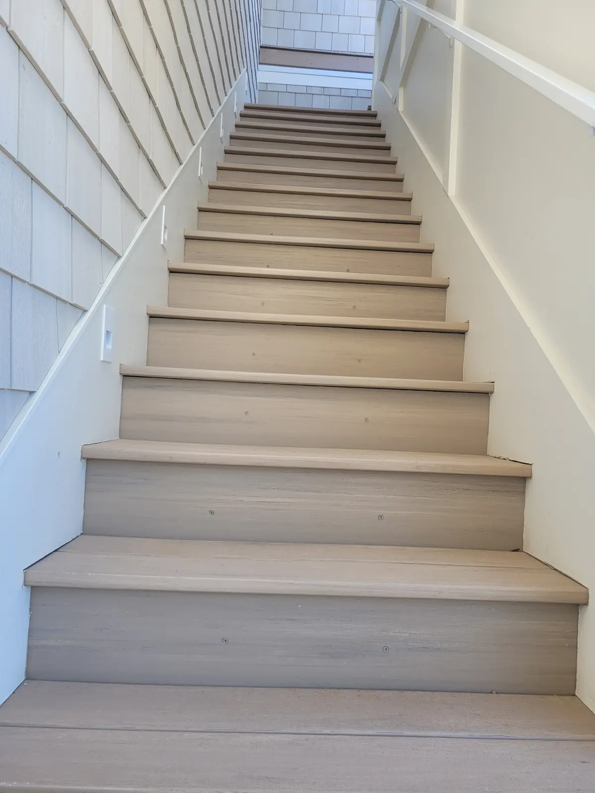 Long enclosed composite staircase with white railing in Provo
