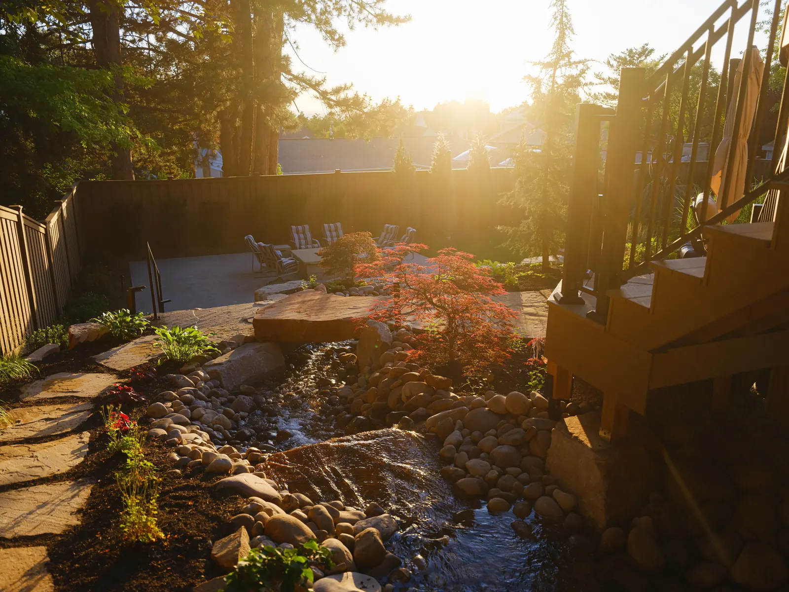 Composite deck stairs beside a backyard stream at sunset