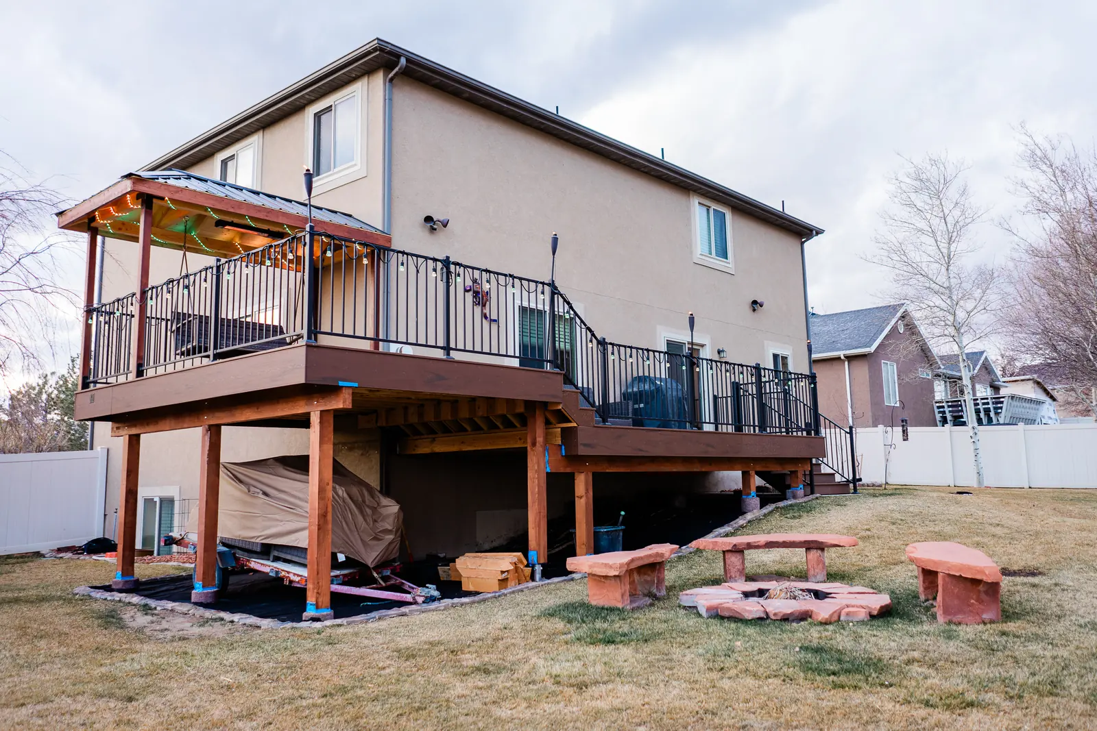 Two-level TimberTech deck with a covered swing area above a backyard fire pit
