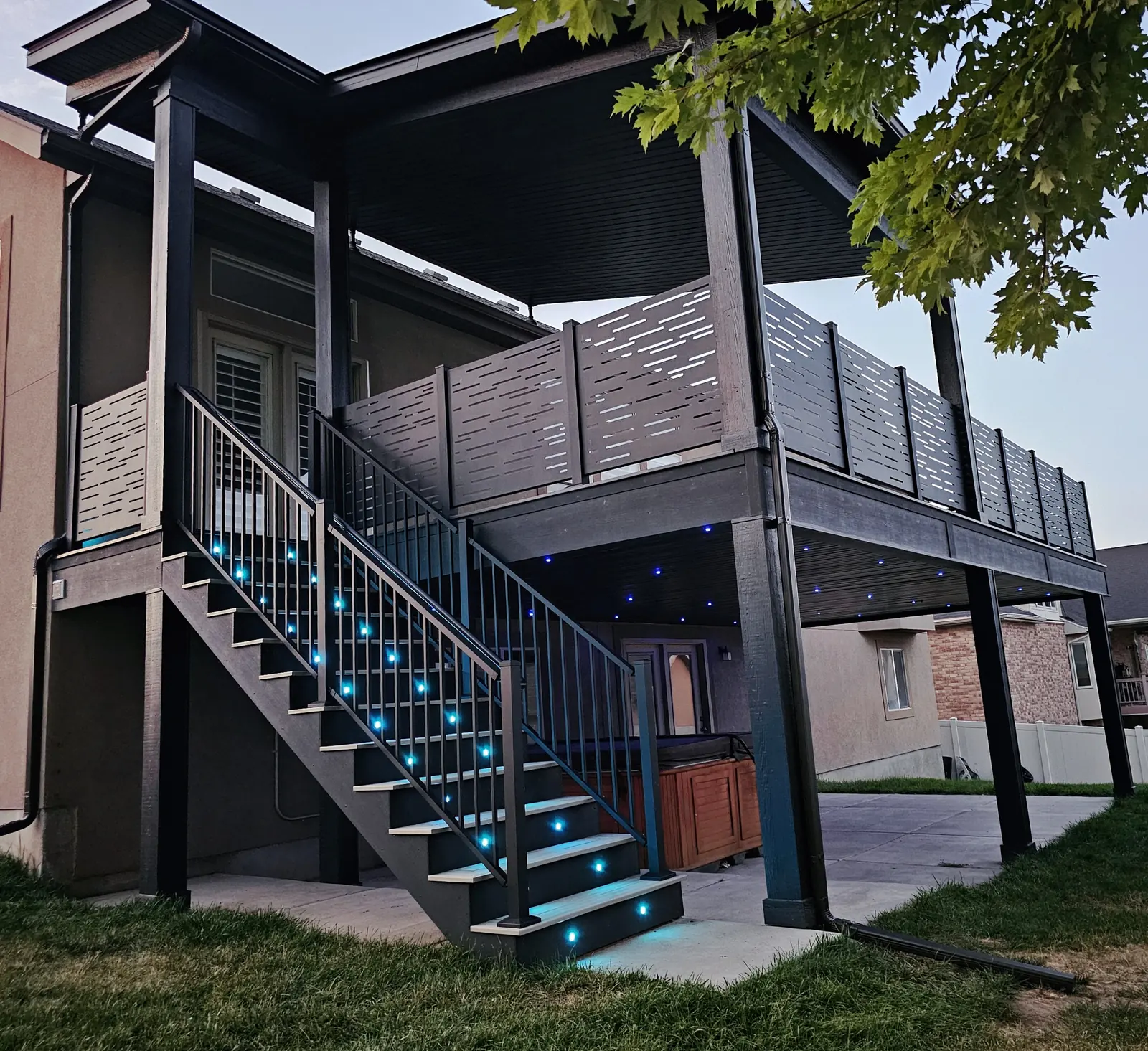 Covered deck with black privacy railing and turquoise lights built by TC Decks in South Jordan