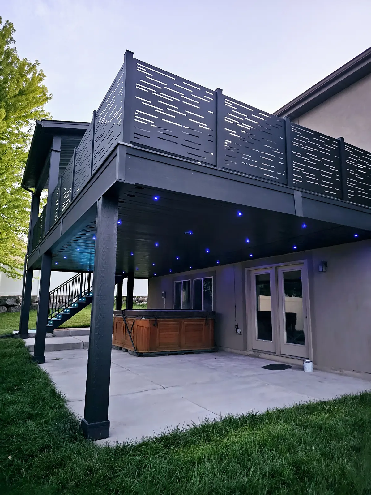 Second-story deck with black privacy railing and blue fiber optic lights underneath in South Jordan, Utah