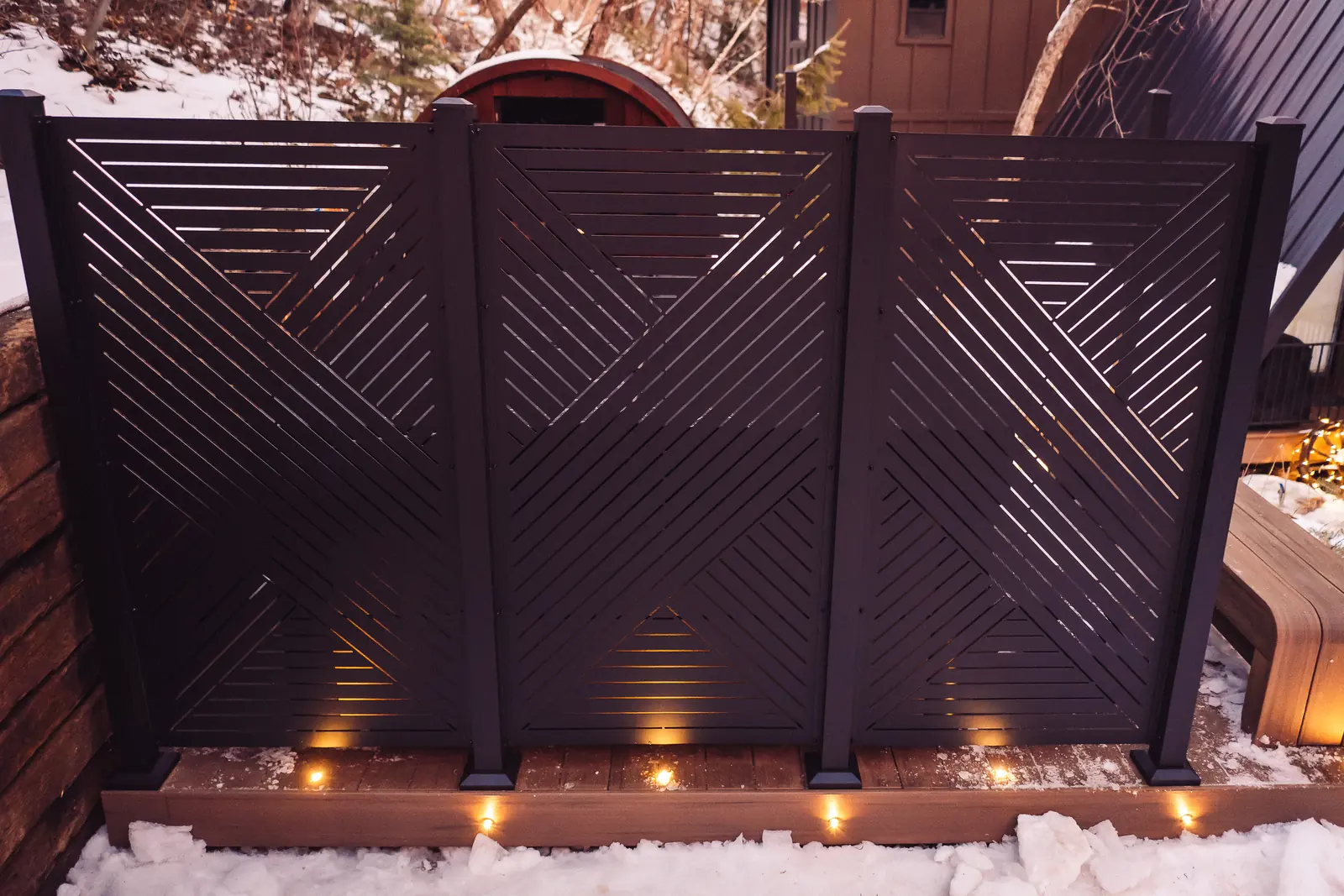 Black privacy screen panels above recessed deck lights in the snow