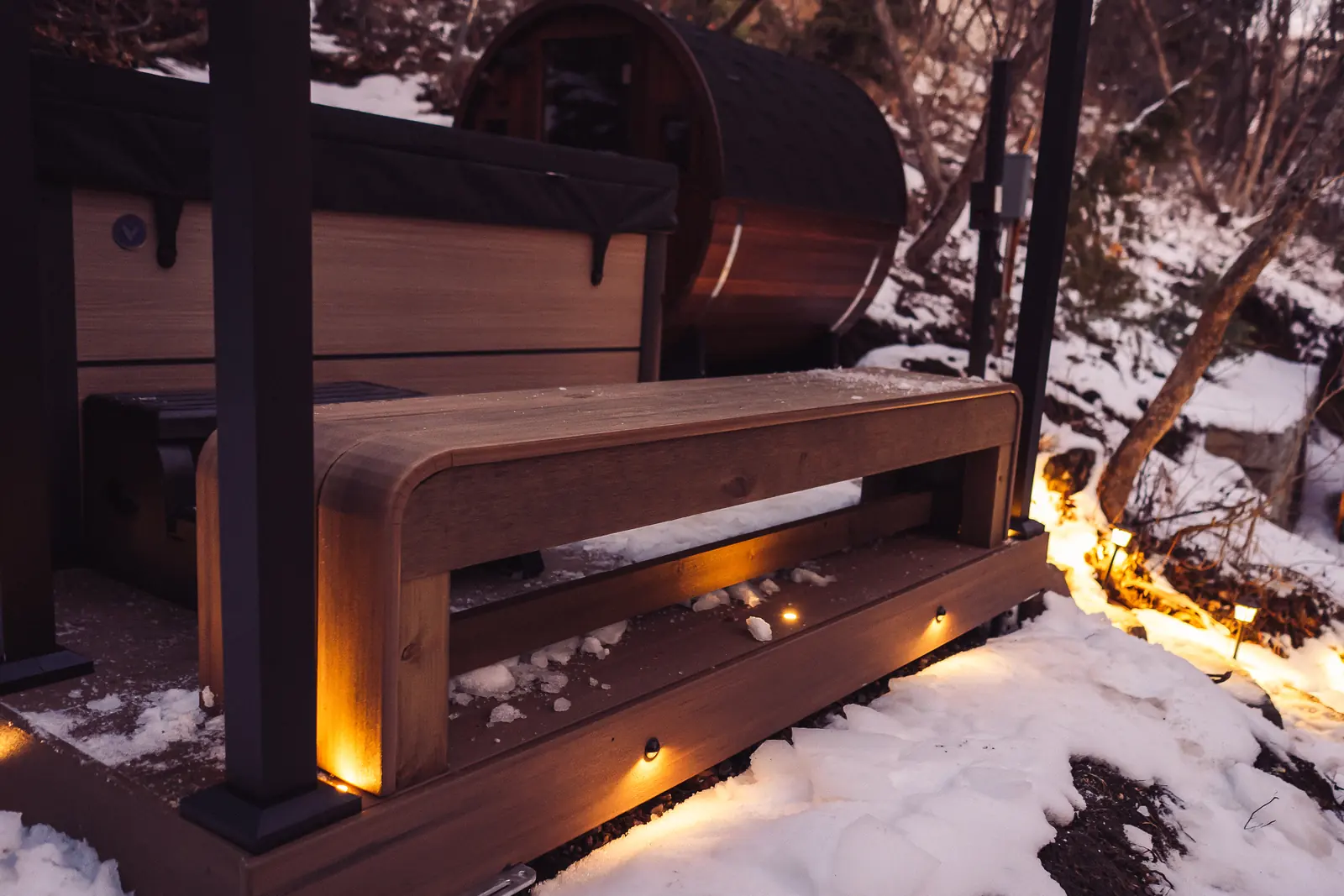 Waterfall bench on a snowy sauna deck with recessed lights